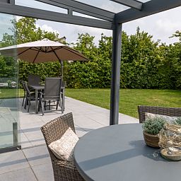 Ontspan op het terras van Vakantiehuis D 427 in De Cocksdorp, Texel, met uitzicht op een groene tuin en comfortabele zitplaatsen.