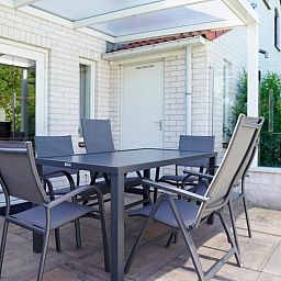 Ontspan op het terras van Vakantiehuis D 415 in De Cocksdorp, Texel, met comfortabele stoelen en een serene tuinomgeving.