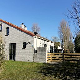 Das Ferienhaus D640 in De Cocksdorp, Texel, bietet einen charmanten Aussenbereich mit einem grossen Garten und einem Holzzaun, ideal fuer einen entspannten Aufenthalt.
