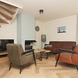 Gemuetliches Wohnzimmer des Ferienhauses D640 in De Cocksdorp, Texel, mit bequemer Sitzecke und modernem Kamin.