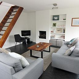 Gezellige woonkamer in Vakantiehuis A 351, De Cocksdorp, Texel met moderne inrichting en open haard voor een ontspannen verblijf op de Waddeneilanden.