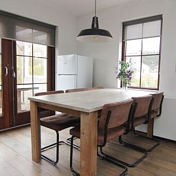 Gemuetliche Essecke im Ferienhaus D 401 in De Cocksdorp, Texel, mit Holztisch und Blick auf den Garten der Watteninseln.