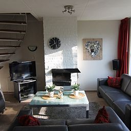 Gezellige woonkamer van Vakantiehuis D 720 in De Cocksdorp, Texel, met comfortabele banken en een sfeervolle open haard.
