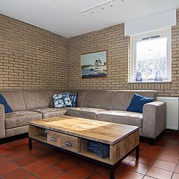 Gezellige woonkamer van Vakantiehuis A 267 in De Cocksdorp, Texel, met comfortabele zitbank en warme sfeer.