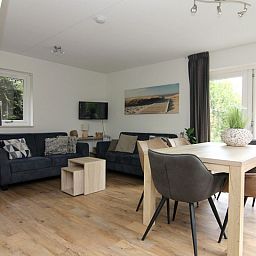 Gezellige woonkamer in Vakantiehuis A 287 in De Cocksdorp, Texel. Comfortabele zithoek en eetruimte met uitzicht op de groene omgeving.