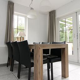 Gezellige eetkamer in Vakantiehuis D 533, De Cocksdorp, Texel, met uitzicht op de tuin via grote ramen, ideaal voor een ontspannen verblijf.