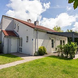 Das Ferienhaus D 756 in De Cocksdorp, Texel, bietet einen schoenen Aussenbereich mit Terrasse und gruenem Garten, ideal fuer einen entspannten Aufenthalt.