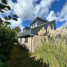 Vakantiehuis A 227 in De Cocksdorp, Texel, toont moderne architectuur omgeven door weelderige natuur op de Waddeneilanden.