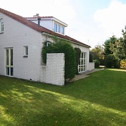 Das Ferienhaus D 760 in De Cocksdorp, Texel, bietet eine ruhige Gartenumgebung mit gruenem Rasen und Privatsphaere fuer einen entspannten Aufenthalt.
