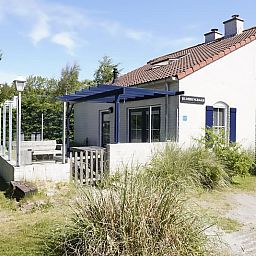 Vakantiehuis D 696 in De Cocksdorp, Texel met zonnige veranda en groene omgeving, ideaal voor een ontspannen verblijf op de Waddeneilanden.