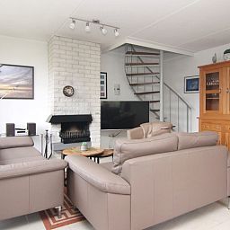 Gezellige woonkamer van Vakantiehuis D 521 in De Cocksdorp, Texel, met comfortabele banken en een sfeervolle open haard.