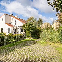 Vakantiehuis D 694 in De Cocksdorp, Texel, omgeven door weelderige natuur en een uitnodigende tuin met groen uitzicht.