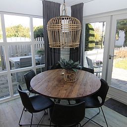 Gezellige eetruimte in Vakantiehuis D 694, De Cocksdorp, Texel met uitzicht op de tuin en terras, ideaal voor een ontspannen verblijf.