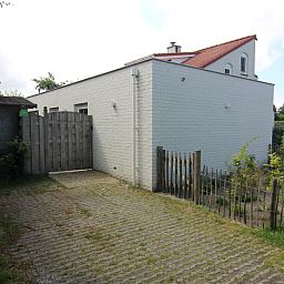 Das Ferienhaus D 671 in De Cocksdorp, Texel, bietet einen ruhigen Aussenbereich mit eingezaeuntem Garten und Tor, ideal fuer Entspannung auf den Watteninseln.