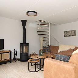 Gemuetliches Wohnzimmer des Ferienhauses D 671 in De Cocksdorp, Texel. Komfortable Sitzecke mit Holzofen fuer eine gemuetliche Urlaubsatmosphaere.