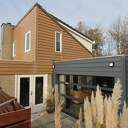 Vakantiehuis B 015 in De Cocksdorp op Texel, Waddeneilanden, met moderne architectuur en ruime veranda omgeven door natuurlijke schoonheid.
