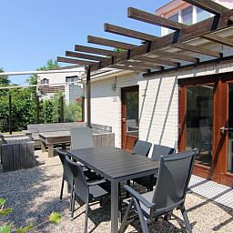 Geniet van het zonnige terras van Vakantiehuis D 662 in De Cocksdorp, Texel, met comfortabele zitplaatsen en een serene tuinomgeving.