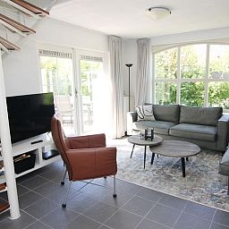 Gezellige woonkamer van Vakantiehuis E 724 in De Cocksdorp, Texel. Comfortabele zithoek met uitzicht op de groene tuin van de Waddeneilanden.