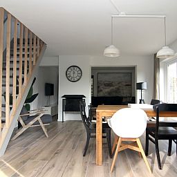 Modern dining room in Holiday home A 075, De Cocksdorp, Texel. Spacious indoor space with wooden floor and stylish furnishings, ideal for relaxation.