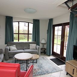Gezellige woonkamer in Vakantiehuis E 655, De Cocksdorp, Texel. Comfortabele zithoek met uitzicht op de groene tuin van de Waddeneilanden.