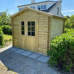 Gartenhaus aus Holz im Ferienhaus D 657 in De Cocksdorp, Texel, umgeben von gruener Natur auf den Watteninseln.