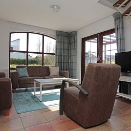 Cozy living room in Holiday home E 645, De Cocksdorp, Texel. Comfortable interior with spacious seating area and views of the green surroundings.