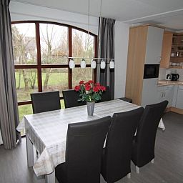 Gezellige eetkamer in Vakantiehuis E 407, De Cocksdorp, Texel met uitzicht op tuin en moderne keuken, ideaal voor familievakanties op de Waddeneilanden.