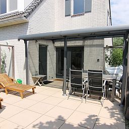 Geniet van het zonnige terras bij Vakantiehuis F 654 in De Cocksdorp, Texel, met comfortabele ligstoelen en een overdekte eetruimte.