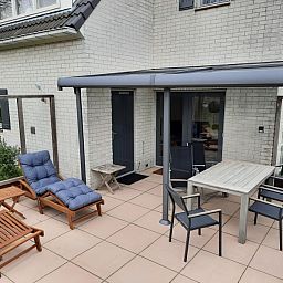 Vakantiehuis F 654 in De Cocksdorp, Texel biedt een uitnodigend terras met comfortabele ligstoelen en een eettafel voor ontspanning in de buitenlucht.