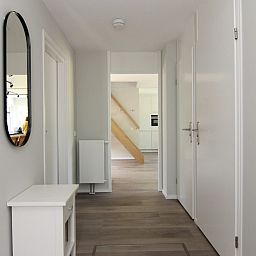 Helle Diele im Ferienhaus F 775, De Cocksdorp, Texel. Moderne Einrichtung mit Holzboden und Zugang zur Kueche.