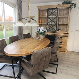 Gezellige eetkamer in Vakantiehuis F 604, De Cocksdorp, Texel, met houten tafel en ruime stoelen, ideaal voor familiebijeenkomsten.