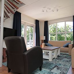 Gezellige woonkamer van Vakantiehuis F 686 in De Cocksdorp, Texel, met comfortabele zithoek en uitzicht op de groene omgeving.