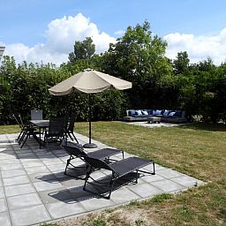 Geniet van het terras van Vakantiehuis E 614 in De Cocksdorp, Texel met comfortabele ligstoelen en een uitnodigende tuinomgeving.