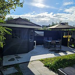 Enjoy the sun on the terrace of Holiday home E 525 in De Cocksdorp, Texel, with comfortable seating and green surroundings.