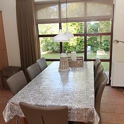 Gemuetliches Esszimmer im Ferienhaus F 713, De Cocksdorp, Texel mit Blick auf den gruenen Garten, ideal fuer einen entspannten Aufenthalt auf den Watteninseln.