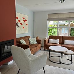 Gezellige woonkamer in Vakantiehuis F 765, De Cocksdorp, Texel met comfortabele zitbanken en uitzicht op de groene tuin.