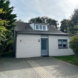 Vakantiehuis E 397 in De Cocksdorp, Texel, biedt een charmante buitenaanblik met groene omgeving voor een ontspannen eilandverblijf.