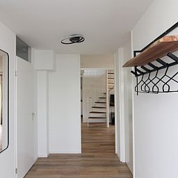 Ingang van Vakantiehuis E 397 in De Cocksdorp, Texel met moderne hal en stijlvolle kapstok, ideaal voor een ontspannen verblijf op de Waddeneilanden.