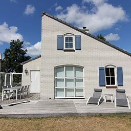 Vakantiehuis E 634 in De Cocksdorp, Texel biedt een zonnig terras met comfortabele ligstoelen en een schilderachtig uitzicht op de natuur.