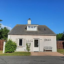Vakantiehuis E 409 in De Cocksdorp, Texel biedt een charmante buitenkant met een uitnodigend terras en groene omgeving.