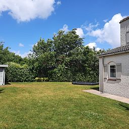 Ruime tuin van Vakantiehuis E 409 in De Cocksdorp, Texel, omgeven door groene natuur voor een ontspannen verblijf op de Waddeneilanden.