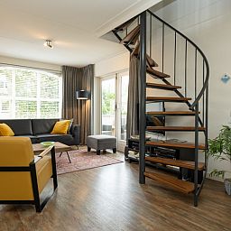 Cozy living room in Holiday home E 541, De Cocksdorp, Texel with modern furnishings and spiral staircase, ideal for a relaxing stay.