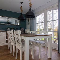 Gezellige eetkamer in Vakantiehuis F 602, De Cocksdorp, Texel, met houten tafel, witte stoelen en uitzicht op de groene tuin.