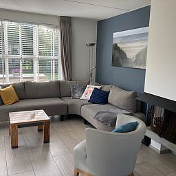 Gezellige woonkamer van Vakantiehuis E 501 in De Cocksdorp, Texel, met comfortabele zithoek en uitzicht op de groene omgeving.