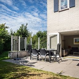 Geniessen Sie den sonnigen Garten und die Terrasse des Ferienhauses E 511 in De Cocksdorp, Texel, ideal fuer einen entspannten Aufenthalt auf den Watteninseln.