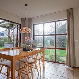 Gezellige eetruimte in vakantiehuis Annemein, De Cocksdorp, Texel, met uitzicht op de tuin en veel natuurlijk licht.