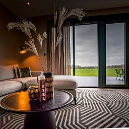 Uitzicht vanuit de woonkamer van 6 persoons vakantiewoning in De Cocksdorp, Texel met groot raam naar terras.