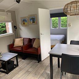 Gezellige woonkamer van vakantiehuis Hoog Koog 12 in Bungalowpark Hoog Koog, De Koog, Texel, met comfortabele zithoek en eethoek.