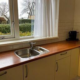 Moderne keuken in vakantiehuis Vogelmient 55, De Koog, Texel, met uitzicht op groene omgeving en veel natuurlijk licht.