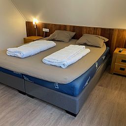 Gezellige slaapkamer in vakantiehuis Vogelmient 55, De Koog, Texel met comfortabel tweepersoonsbed en warme houten accenten.